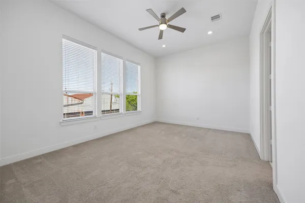 an empty room with windows and ceiling fan