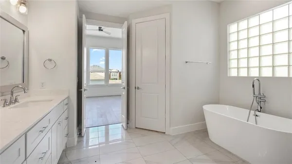 a spacious bathroom with a tub sink and mirror