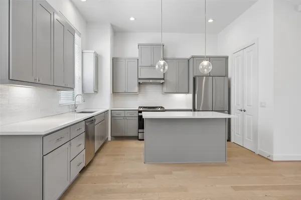 a kitchen with stainless steel appliances granite countertop a stove a sink and a refrigerator