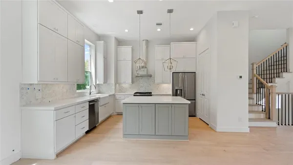 a large kitchen with a large counter top a sink stainless steel appliances and cabinets