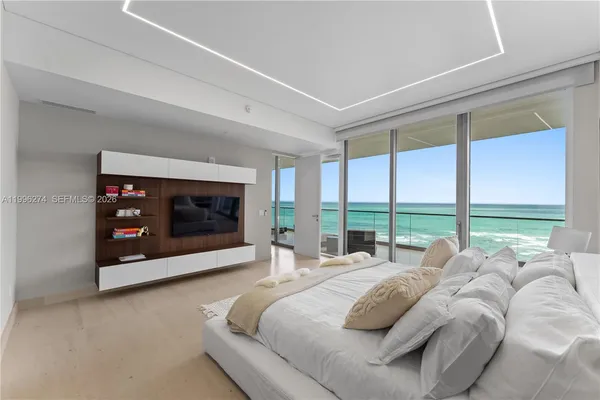 a large bed sitting in a bedroom next to a large window with a flat tv screen and a fireplace next to a window