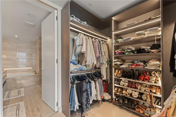 a view of walk in closet with clothes and shoes