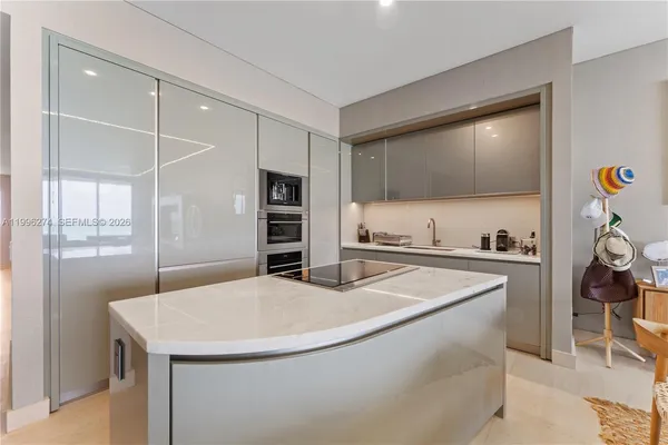 a kitchen with stainless steel appliances a stove a refrigerator a sink and white cabinets with wooden floor