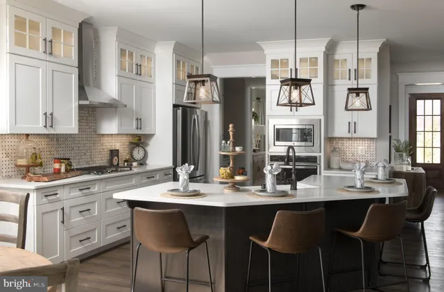a kitchen with stainless steel appliances kitchen island granite countertop a dining table chairs and white cabinets