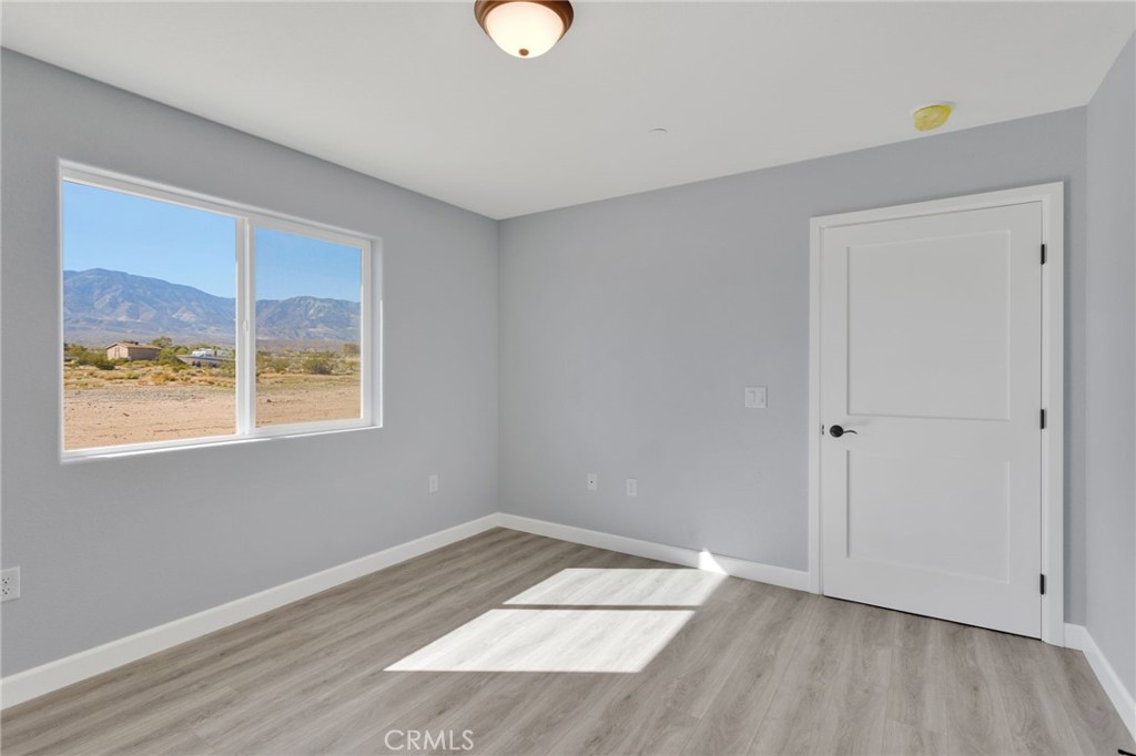 36165 Sutter Road Lucerne Valley, CA 92356 - Photo 17 of 42 a view of an empty room with wooden floor and a window
