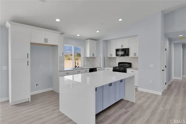 a large kitchen with stainless steel appliances kitchen island a large counter top and a wooden floors