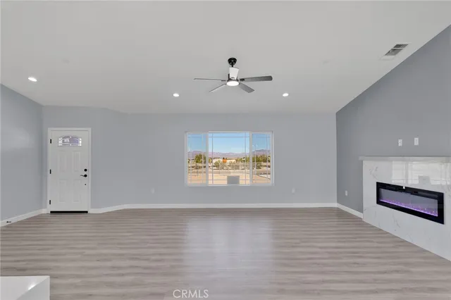 a view of an empty room with a window and a kitchen