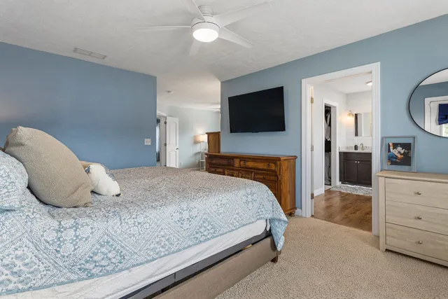 a bedroom with a large bed and a flat tv screen on dresser
