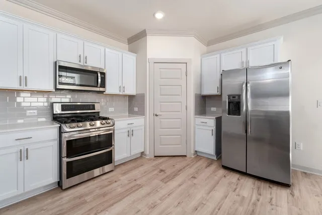 a kitchen with stainless steel appliances and wooden floor