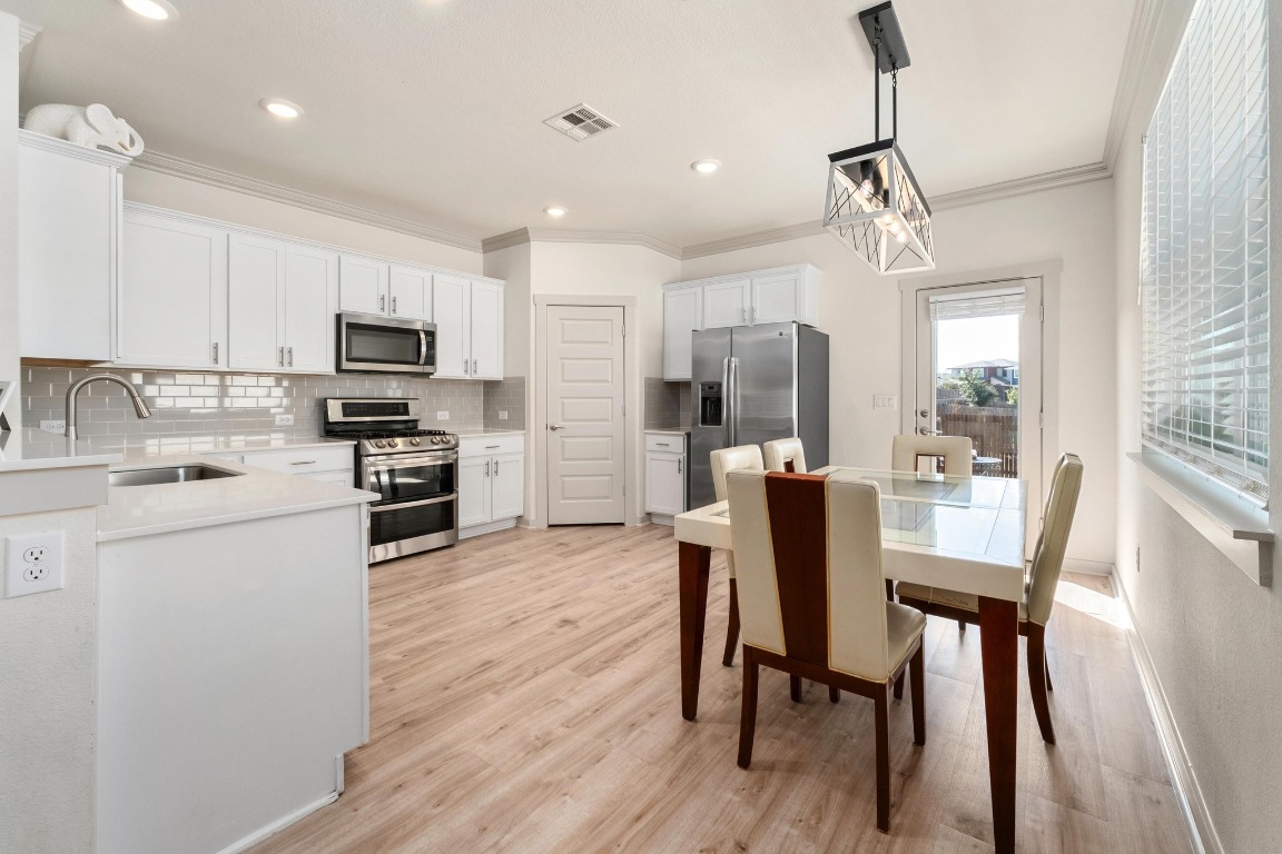 7709 Jacobean Way Austin, TX 78724 - Photo 9 of 23 a kitchen with stainless steel appliances a dining table chairs refrigerator and microwave