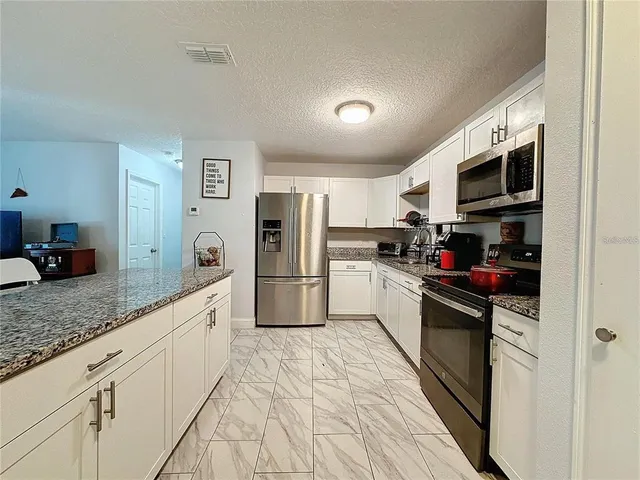 a kitchen with stainless steel appliances granite countertop a refrigerator a stove top oven a sink and dishwasher