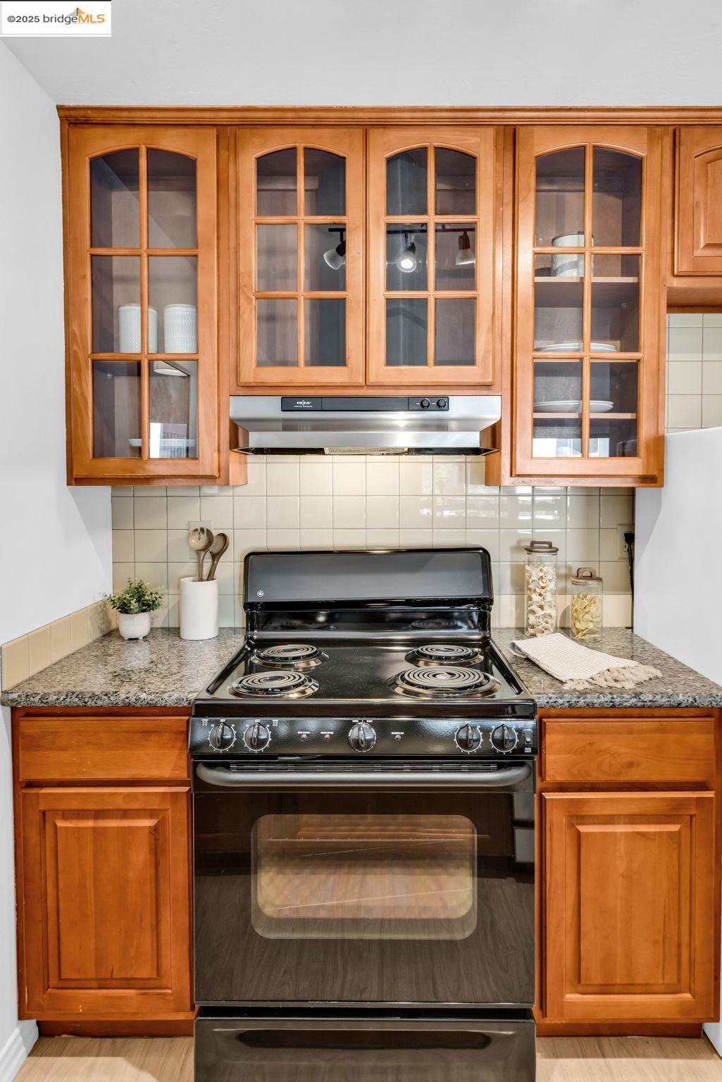 288 Whitmore Street, Unit 220 Oakland, CA 94611 - Photo 20 of 38 Kitchen with black electric range oven, brown cabinets, and decorative backsplash