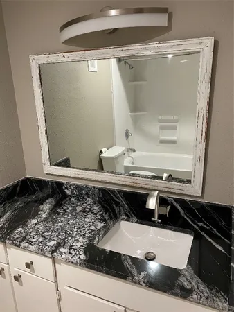 a bathroom with a granite countertop sink and a mirror