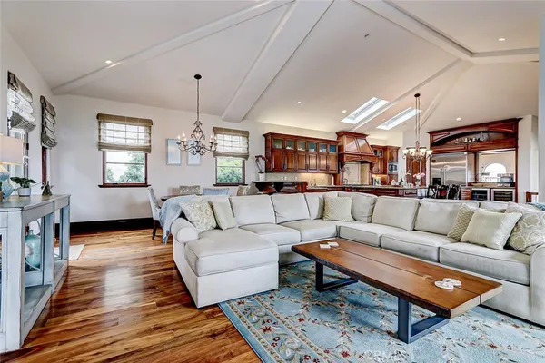 a kitchen with stainless steel appliances granite countertop a stove top oven a sink dishwasher and a dining table with wooden floor