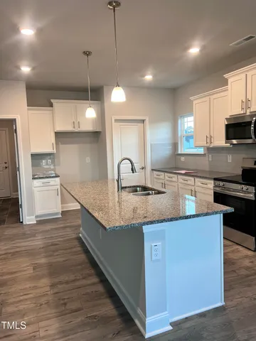 a large kitchen with kitchen island a stove a sink a refrigerator and a wooden floor