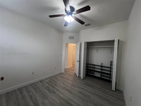 an empty room with wooden floor a ceiling fan and windows