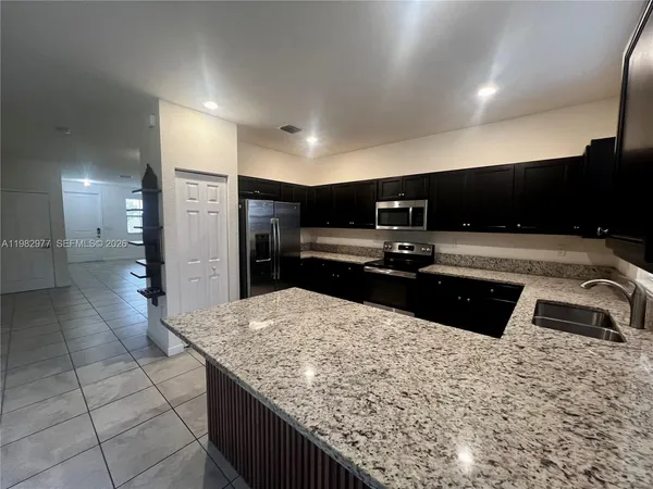 a kitchen with granite countertop a sink and a refrigerator