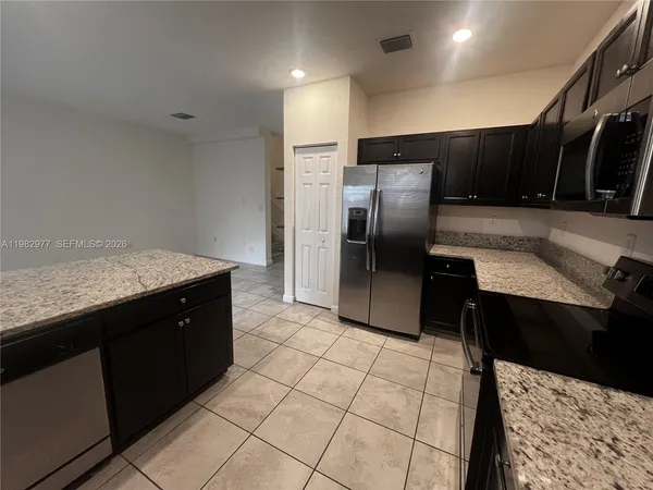 a kitchen with granite countertop a refrigerator and a sink