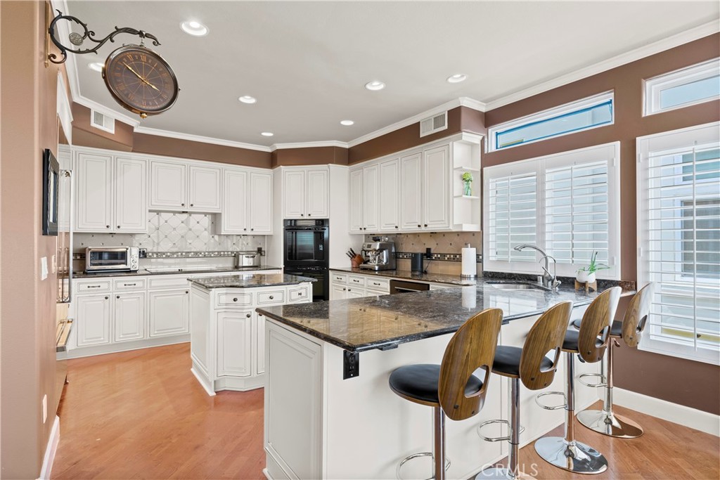 33662 Holtz Hill Drive Dana Point, CA 92629 - Photo 29 of 75 a kitchen with stainless steel appliances granite countertop a stove top oven a sink a dining table and chairs with wooden floor
