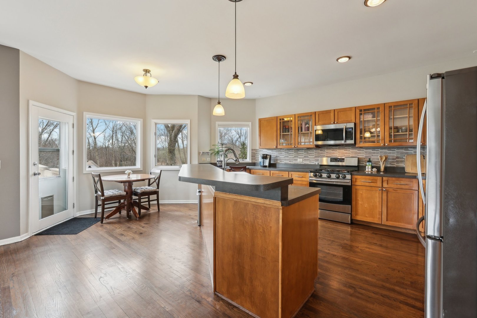 40783 Gridley Drive Antioch, IL 60002 - Photo 9 of 44 a kitchen with stainless steel appliances granite countertop wooden cabinets a refrigerator a stove a sink and a dining table with wooden floor