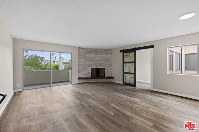 a view of empty room with wooden floor and fireplace