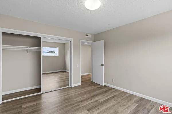 a view of an empty room with wooden floor & closet