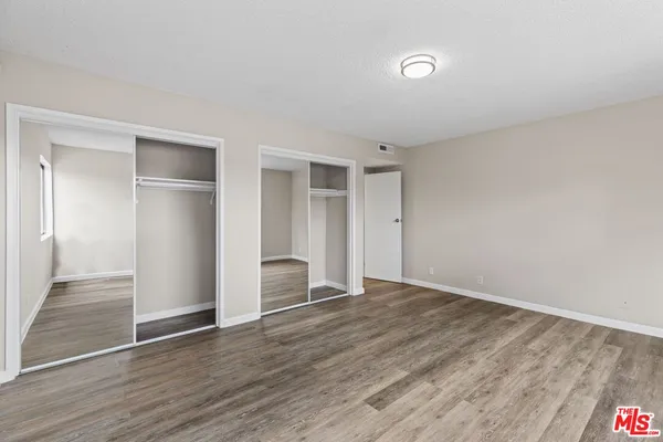 a view of an empty room with wooden floor and closet