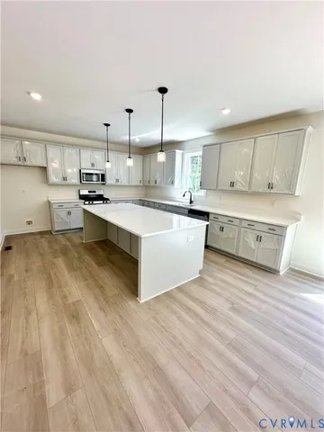 a large room with kitchen island a sink dishwasher a dining table and chairs with wooden floor