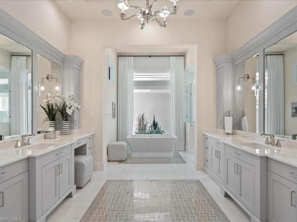 142 Eugenia Drive Naples, FL 34108 - Photo 18 of 35 a bathroom with a double vanity sink a large mirror a bathtub and
