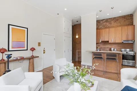 a living room with stainless steel appliances furniture a window and a sink