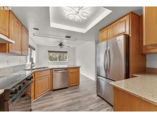 a kitchen with granite countertop stainless steel appliances a refrigerator cabinets and wooden floor