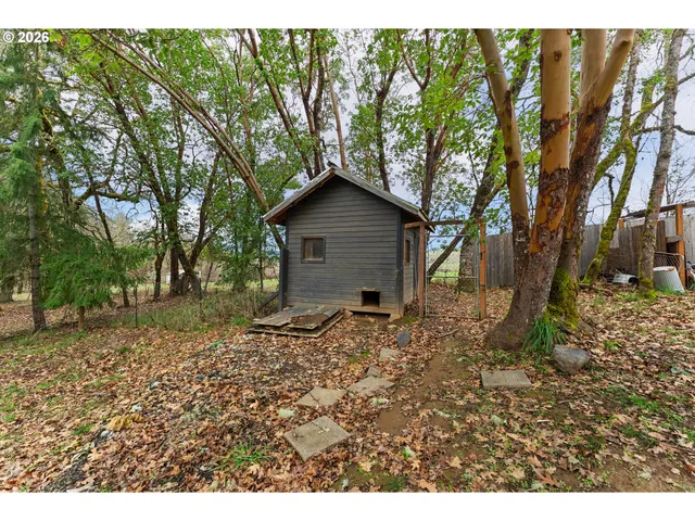 a view of a wooden house with a big yard and large trees