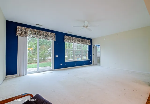 a view of a big room with windows and chandelier fan