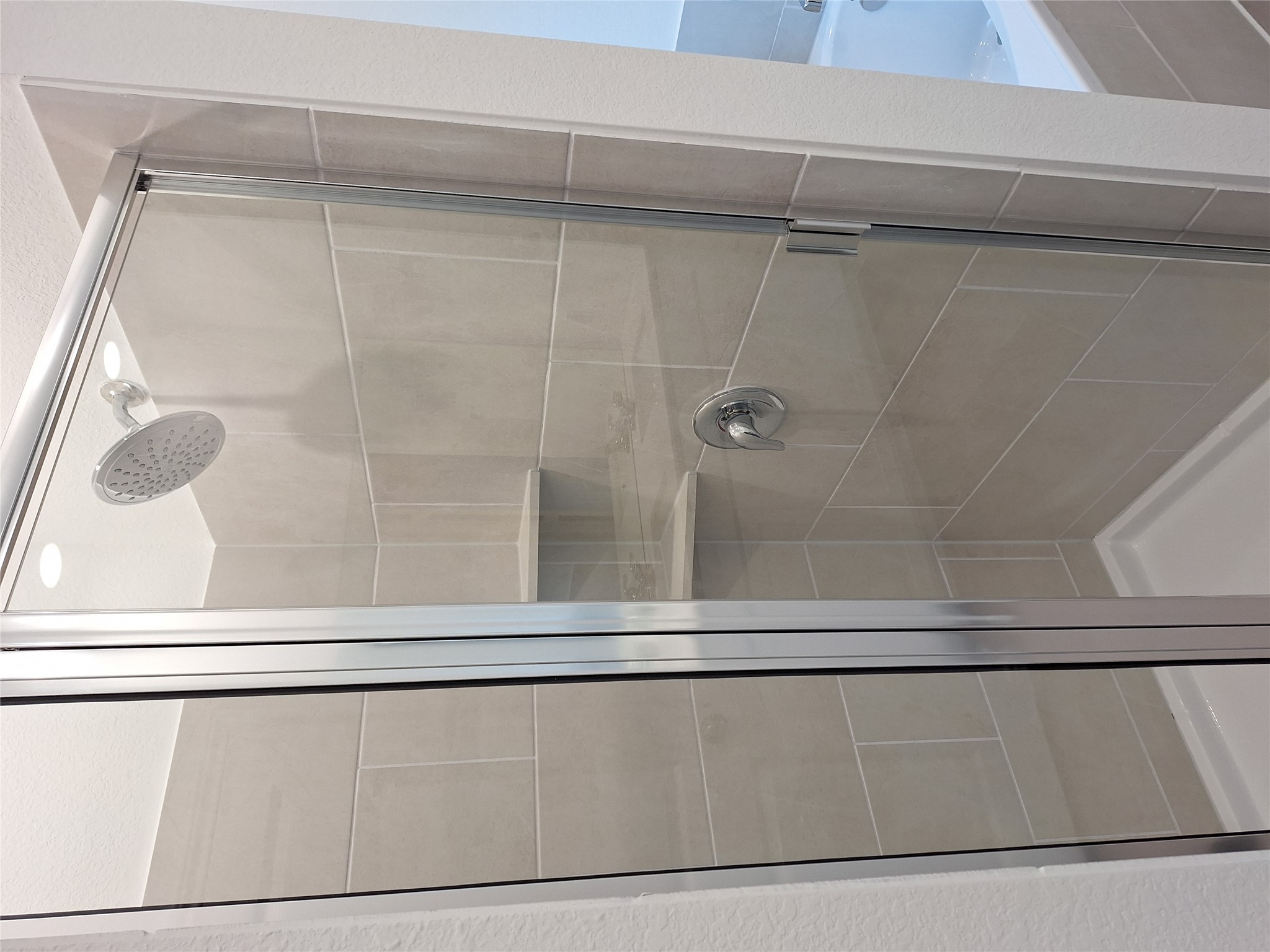 18001 Prairie Falcon Way Pflugerville, TX 78660 - Photo 25 of 38 Enclosed glass shower featuring light-toned rectangular tile surround, a built-in corner shelf, and a chrome rainfall showerhead