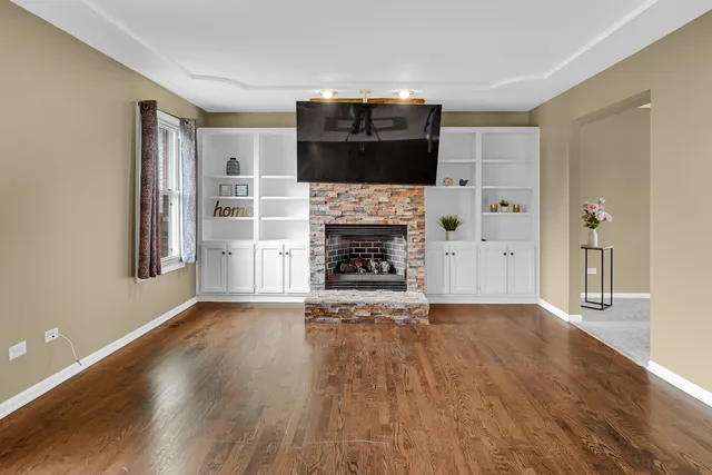 an empty room with wooden floor fireplace and cabinet