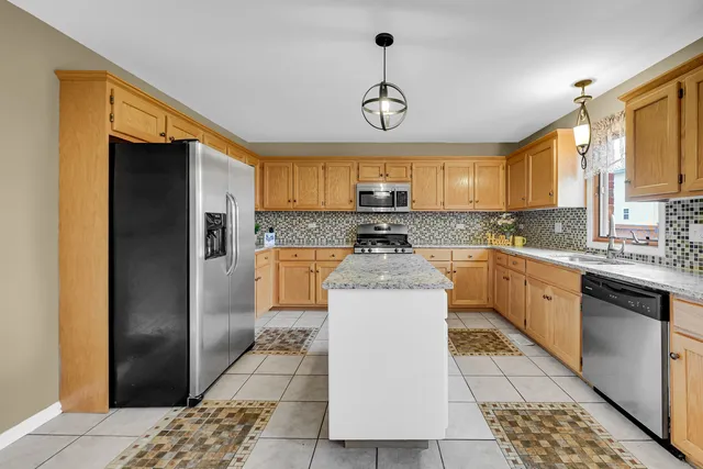 a kitchen with stainless steel appliances granite countertop a refrigerator a sink dishwasher a stove and white cabinets with wooden floor