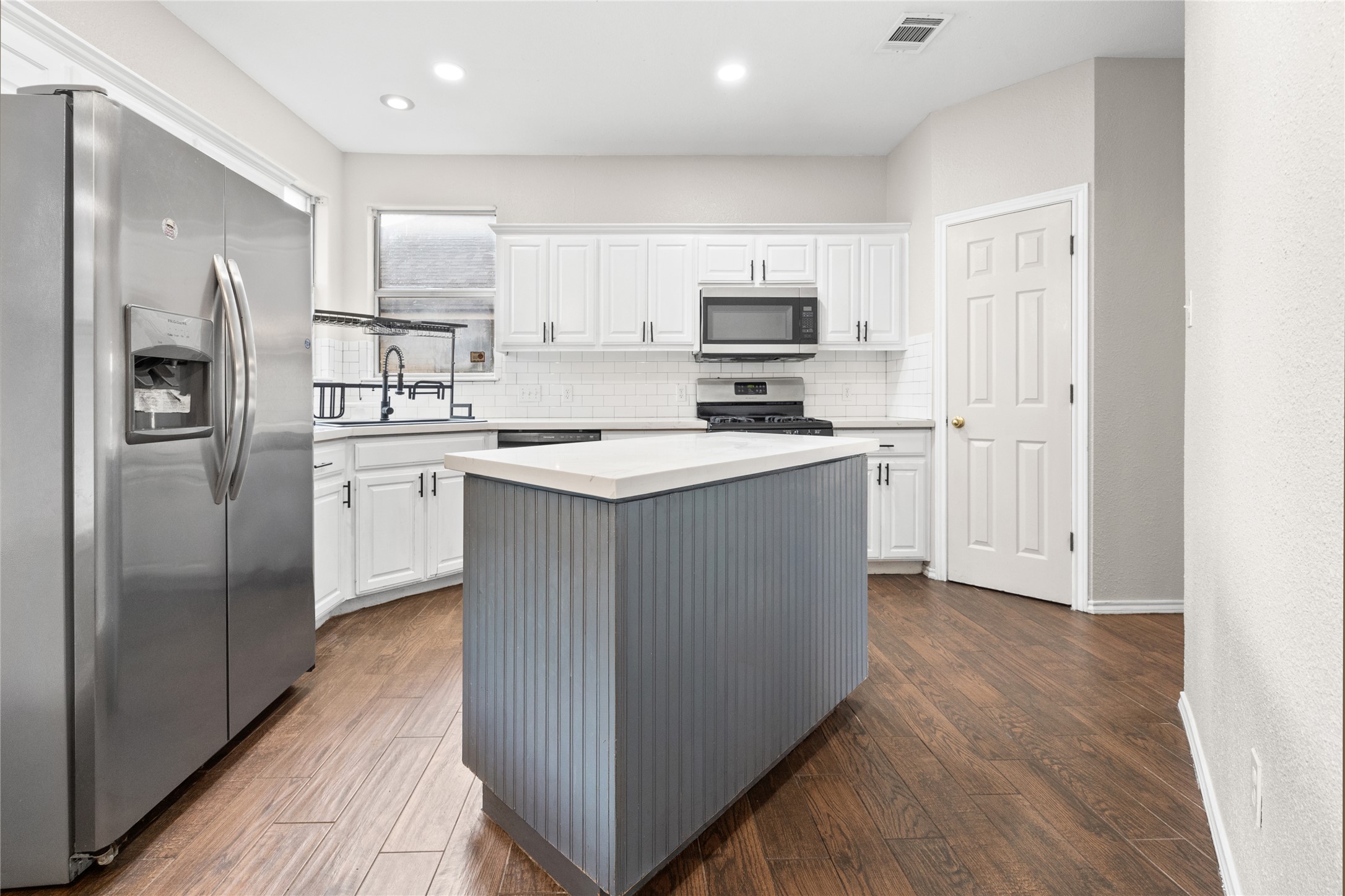 13217 Rochester Lane Austin, TX 78753 - Photo 10 of 30 Rich wood-look flooring sets an inviting tone in this kitchen centered around a functional island.