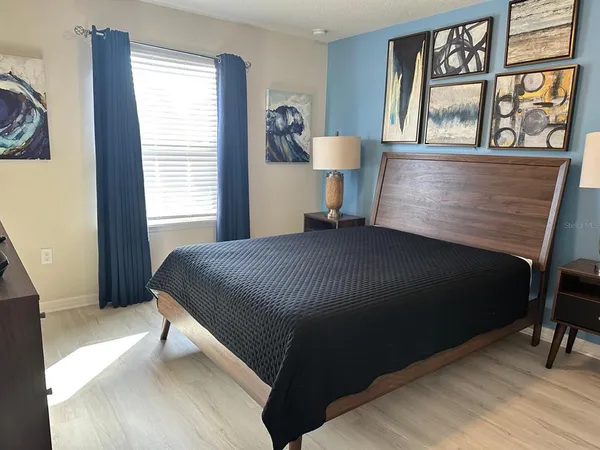 a bedroom with a bed table window and a lamp on table