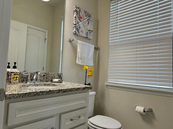 a bathroom with a granite countertop toilet sink and mirror