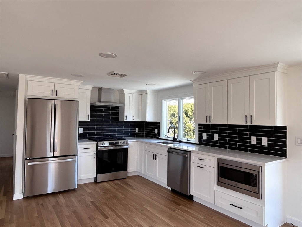 585 North Eastern Avenue Fall River, MA 02720 - Photo 6 of 26 a kitchen with granite countertop a refrigerator a stove a sink and white cabinets