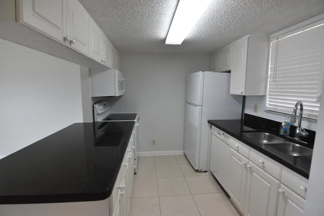 a kitchen with granite countertop a sink a stove and refrigerator