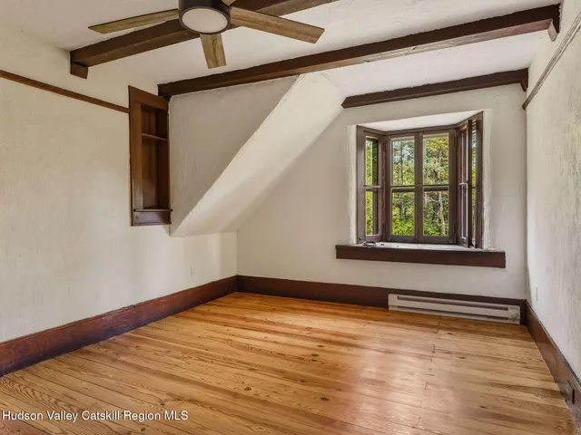 a view of an empty room with a window and wooden floor