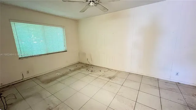 an empty room with a ceiling fan and window