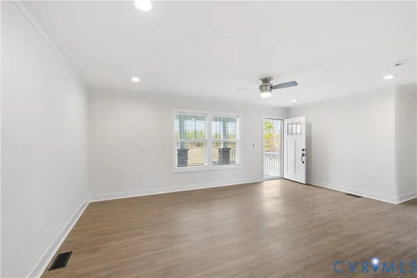 an empty room with wooden floor and windows