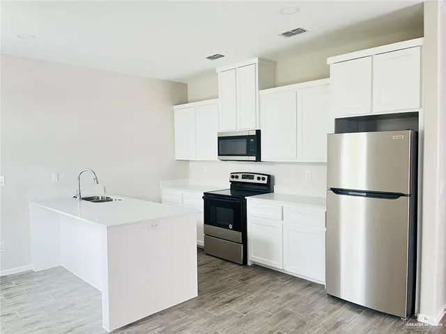 a kitchen with a refrigerator sink and white cabinets