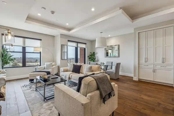 a living room with furniture large window and wooden floor