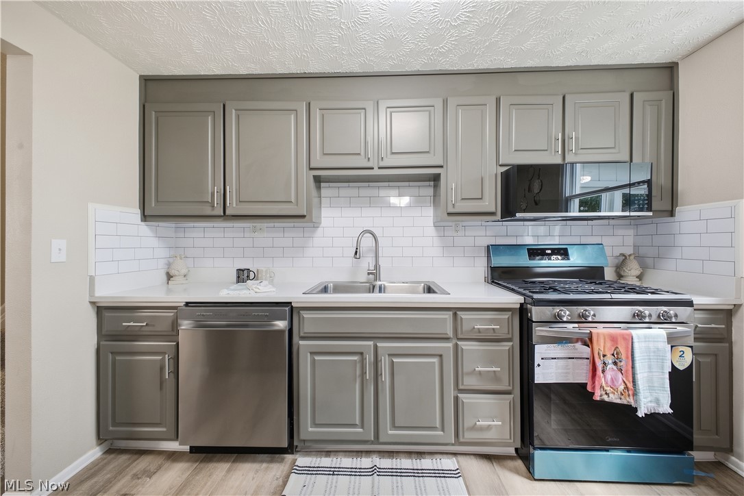 4845 New Road Austintown, OH 44515 - Photo 8 of 40 Kitchen featuring gray cabinetry, white subway tile backsplash, stainless steel appliances, and wood-finish flooring