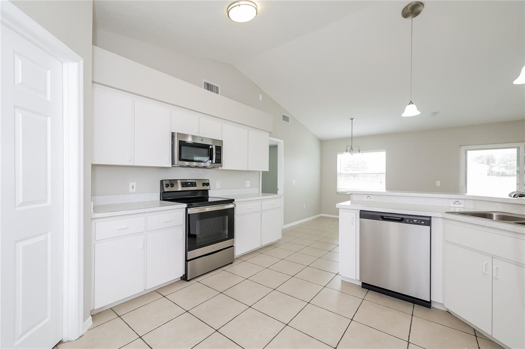 102 Ashley Loop Davenport, FL 33837 - Photo 6 of 16 a kitchen with granite countertop white cabinets and stainless steel appliances