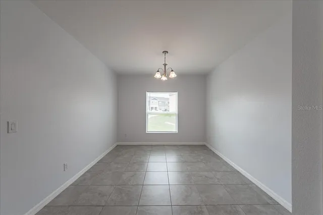 an empty room with a chandelier and a window