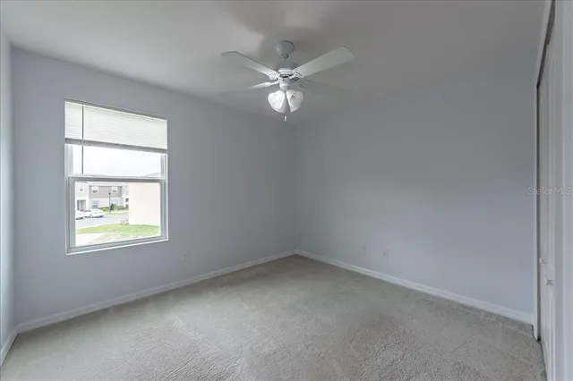an empty room with a window and a fan